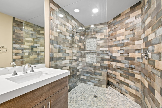 bathroom with a tile shower and vanity