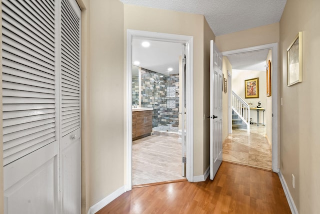 hall featuring wood-type flooring and a textured ceiling