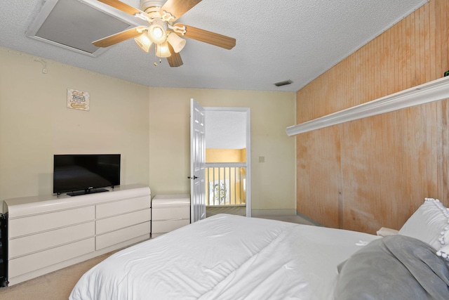 carpeted bedroom featuring ceiling fan, a textured ceiling, and wood walls