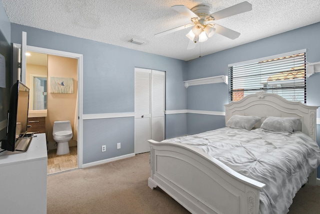 carpeted bedroom featuring a textured ceiling, connected bathroom, ceiling fan, and a closet