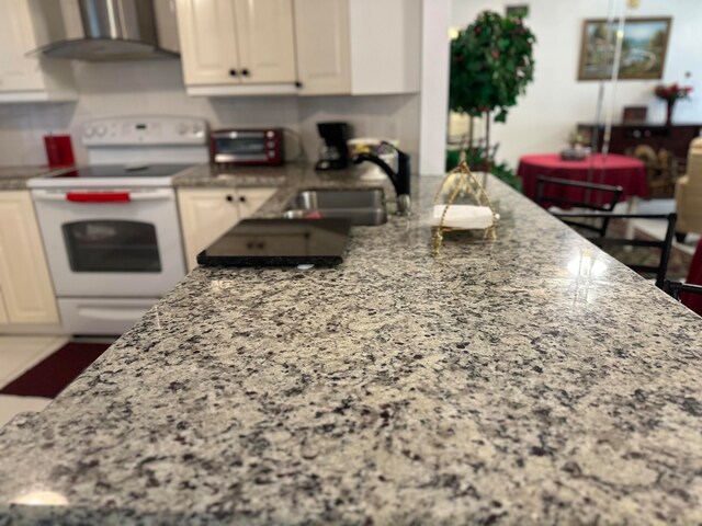 kitchen with white cabinetry, wall chimney range hood, sink, and electric stove