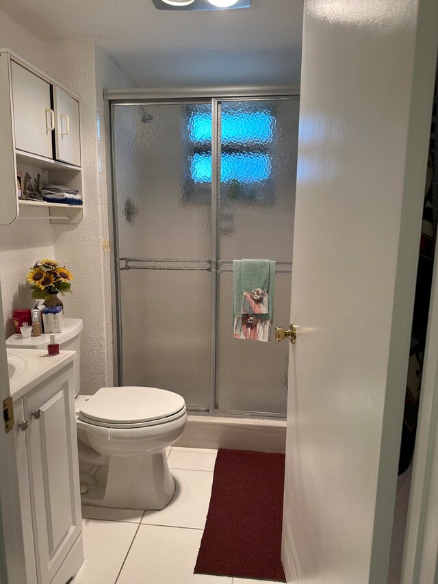 bathroom with tile floors, a shower with shower door, vanity, and toilet