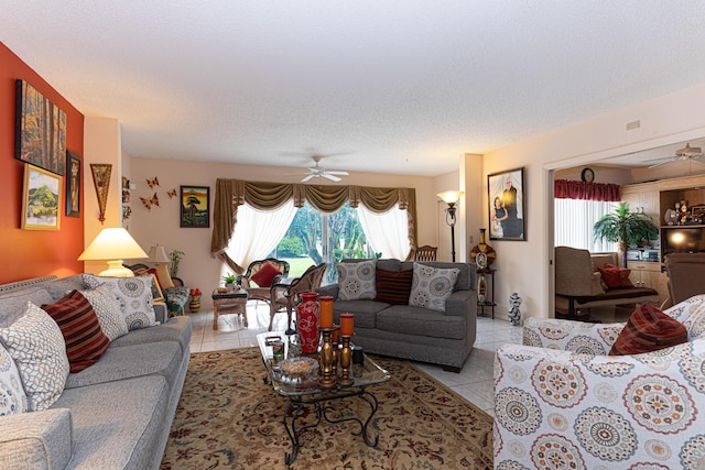 living room with ceiling fan, light tile patterned floors, and a textured ceiling