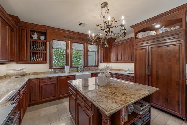 kitchen with an inviting chandelier, light stone counters, pendant lighting, paneled built in fridge, and a kitchen island