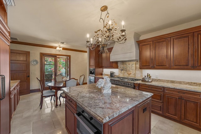 kitchen with stove, premium range hood, pendant lighting, a notable chandelier, and a center island