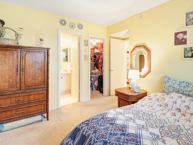 carpeted bedroom featuring a closet, a walk in closet, and ensuite bathroom