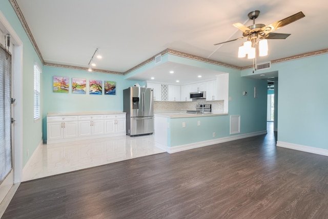 kitchen with wood-type flooring, tasteful backsplash, stainless steel appliances, and white cabinetry