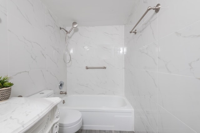 full bathroom with tile walls, vanity, toilet, and tiled shower / bath