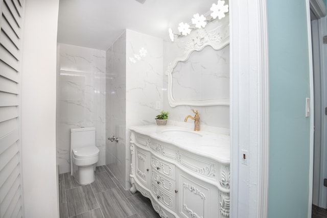 bathroom with tile walls, vanity, tile floors, and toilet