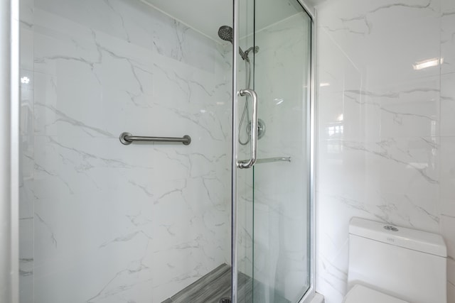 bathroom featuring a shower with shower door and toilet