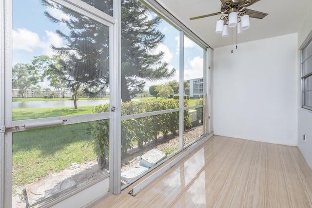 unfurnished sunroom with ceiling fan and a water view