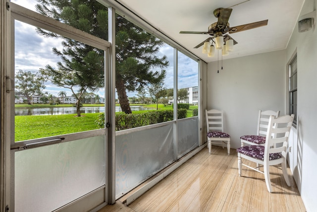 sunroom featuring ceiling fan and a water view