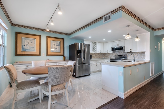 kitchen featuring light wood-type flooring, appliances with stainless steel finishes, backsplash, and white cabinetry