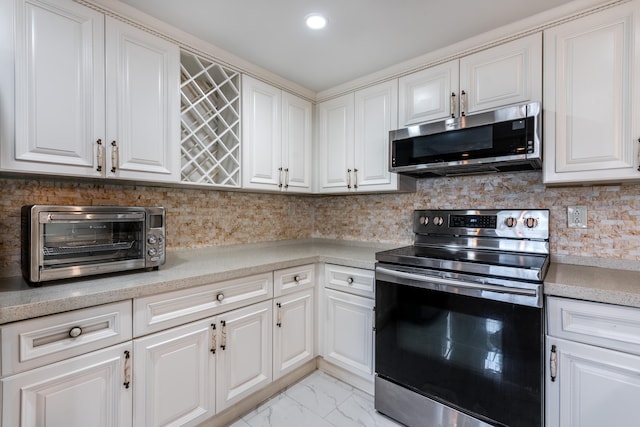 kitchen with appliances with stainless steel finishes, tasteful backsplash, light tile flooring, and white cabinetry