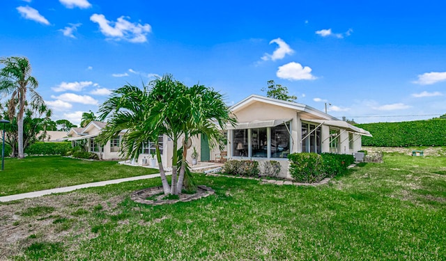 back of property with a sunroom and a lawn