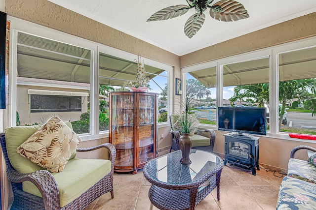 sunroom with ceiling fan and a wood stove