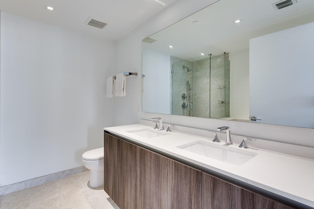 bathroom with an enclosed shower, vanity with extensive cabinet space, toilet, and double sink