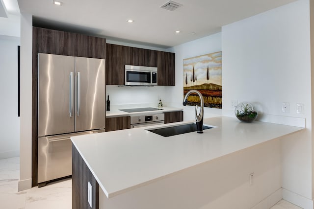 kitchen with sink, appliances with stainless steel finishes, dark brown cabinetry, a center island, and light tile floors