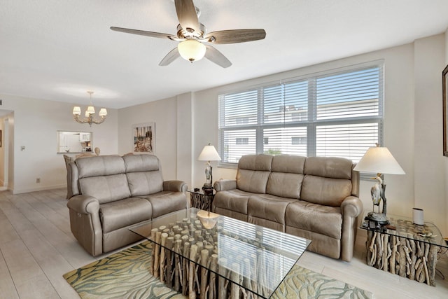 living room with ceiling fan with notable chandelier and light hardwood / wood-style flooring