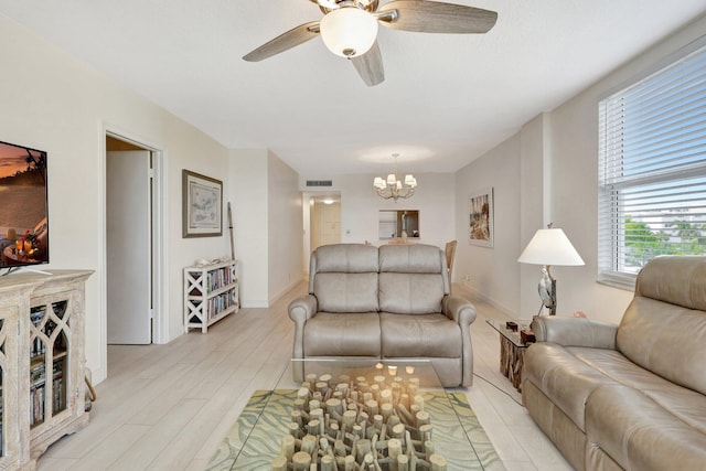 living room with ceiling fan with notable chandelier and light hardwood / wood-style flooring