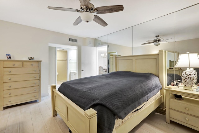 bedroom with ensuite bathroom, light hardwood / wood-style floors, and ceiling fan