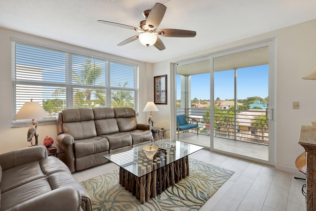 living room featuring ceiling fan, a textured ceiling, and light hardwood / wood-style flooring