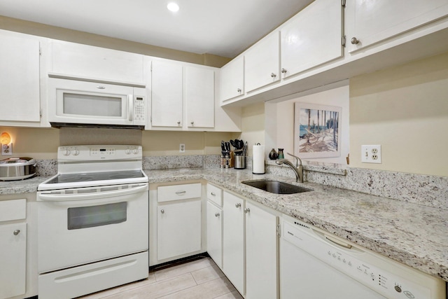 kitchen with light stone counters, white cabinetry, light tile patterned floors, sink, and white appliances