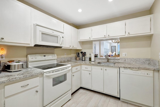 kitchen with a notable chandelier, light stone countertops, sink, white cabinets, and white appliances