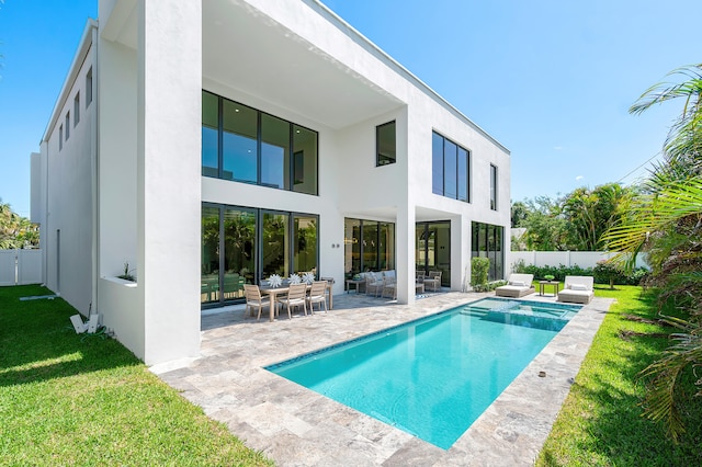 back of property with a fenced in pool, a patio, and a lawn