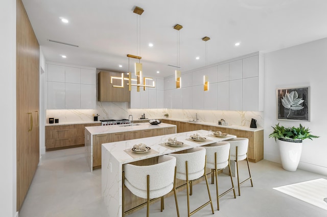 kitchen featuring backsplash, pendant lighting, an island with sink, and white cabinetry