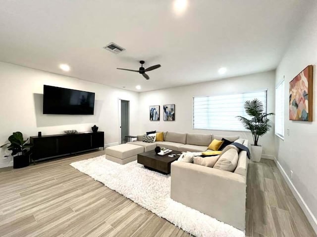 living room featuring a ceiling fan, baseboards, visible vents, and light wood finished floors