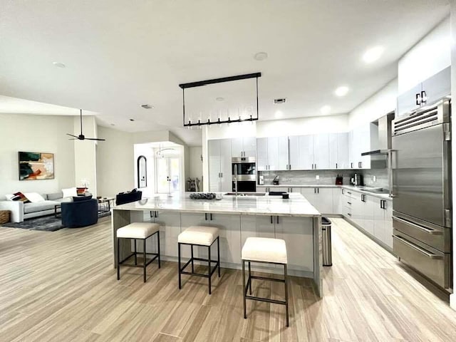 kitchen with white cabinets, a spacious island, a breakfast bar area, hanging light fixtures, and stainless steel appliances