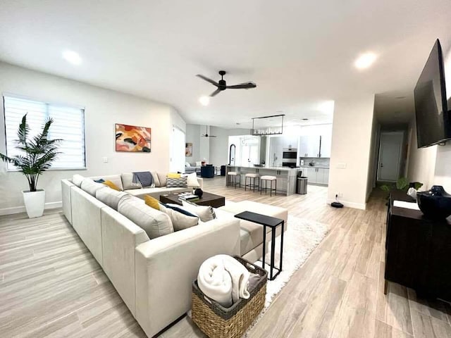 living room featuring light wood-style floors, ceiling fan, baseboards, and recessed lighting