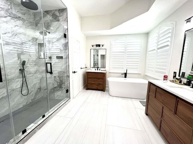 bathroom featuring a sink, a soaking tub, a marble finish shower, and two vanities