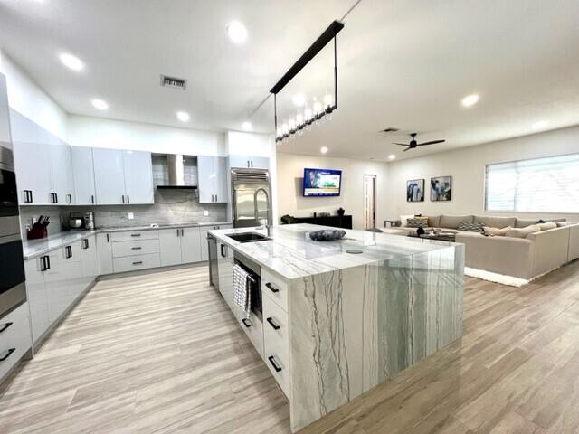 kitchen featuring hanging light fixtures, a spacious island, modern cabinets, and white cabinetry