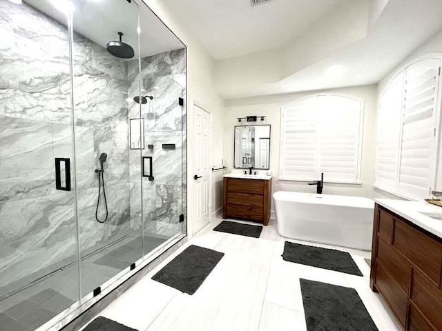 full bath with a marble finish shower, visible vents, two vanities, a freestanding bath, and a sink