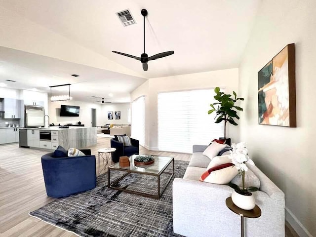 living room featuring ceiling fan, sink, and light hardwood / wood-style floors