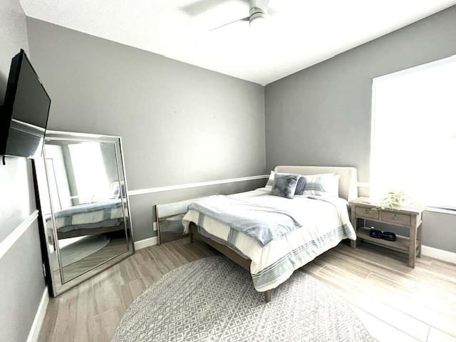 bedroom with a ceiling fan, baseboards, and wood finished floors