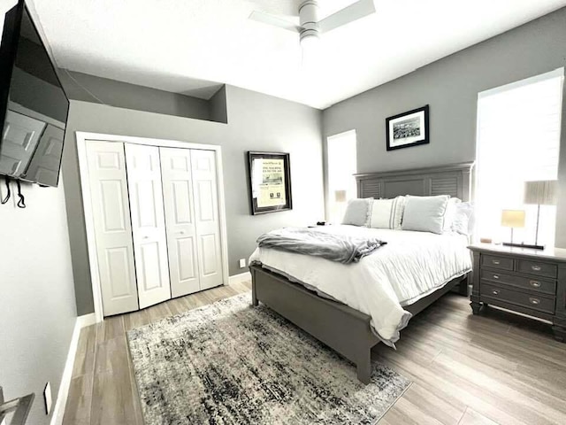 bedroom featuring a ceiling fan, a closet, baseboards, and light wood finished floors