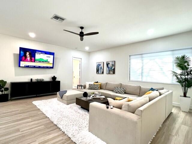 living room featuring light wood-style flooring, visible vents, ceiling fan, and recessed lighting