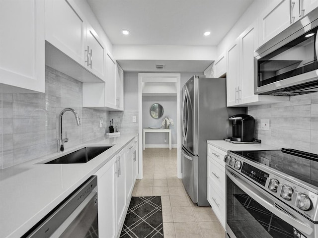 kitchen featuring light tile patterned flooring, sink, appliances with stainless steel finishes, decorative backsplash, and white cabinets