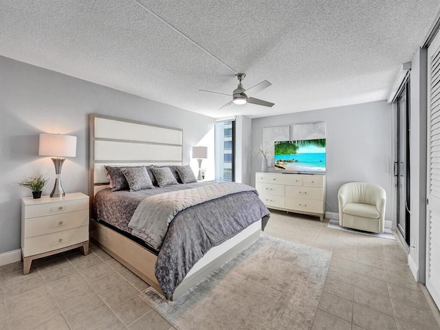 bedroom with ceiling fan, light tile patterned flooring, and a textured ceiling