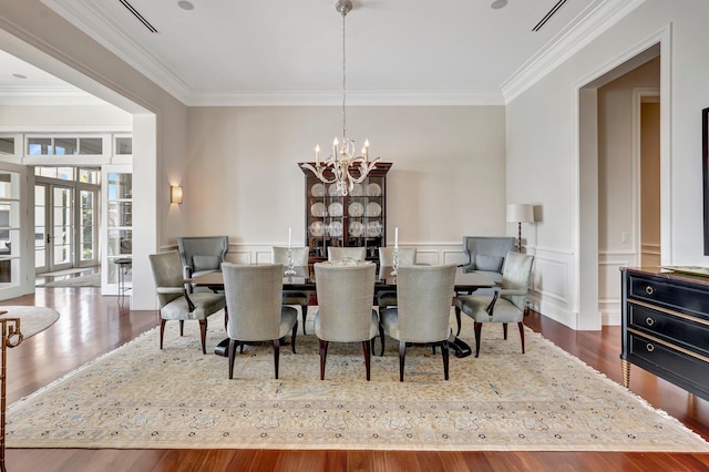 dining room featuring french doors, crown molding, hardwood / wood-style flooring, and a chandelier