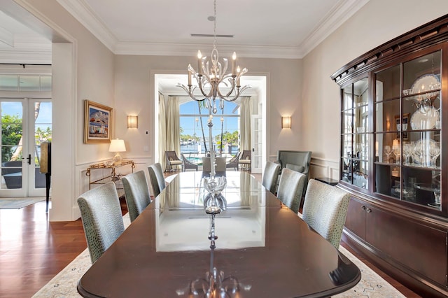 dining room featuring a notable chandelier, wood-type flooring, ornamental molding, and french doors