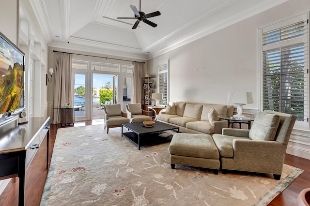 living room with ornamental molding, hardwood / wood-style floors, ceiling fan, vaulted ceiling, and a raised ceiling