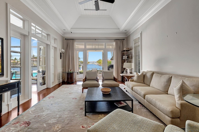 living room featuring a water view, ceiling fan, a tray ceiling, ornamental molding, and wood-type flooring