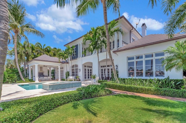 rear view of house with a yard, a patio, and a swimming pool with hot tub