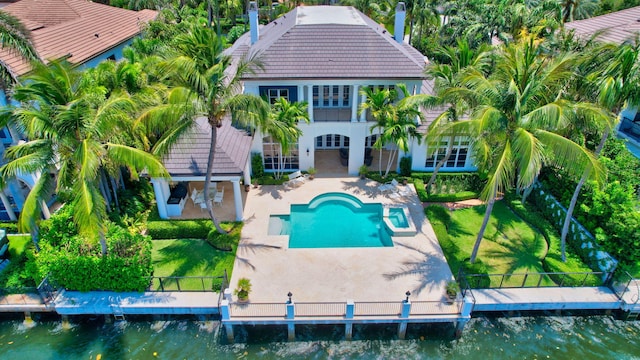 exterior space with a boat dock, a water view, a patio area, and a lawn