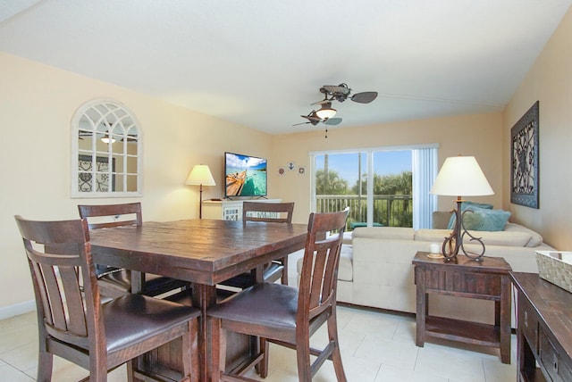 dining area with light tile patterned floors, baseboards, and a ceiling fan