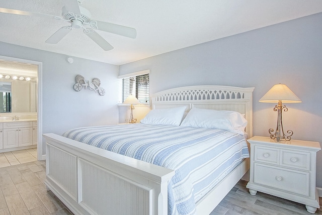 bedroom with ceiling fan, a sink, connected bathroom, and light wood-style floors